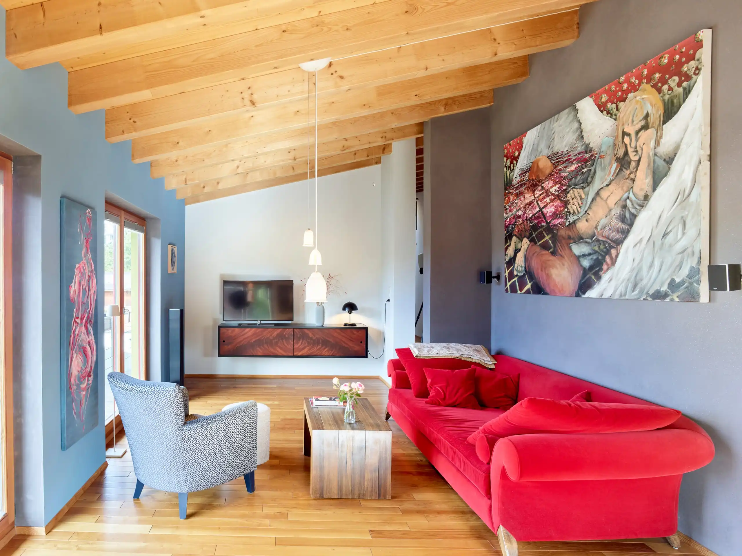 Wohnraum mit Holzdecke, Lehmwänden und rotem Sofa