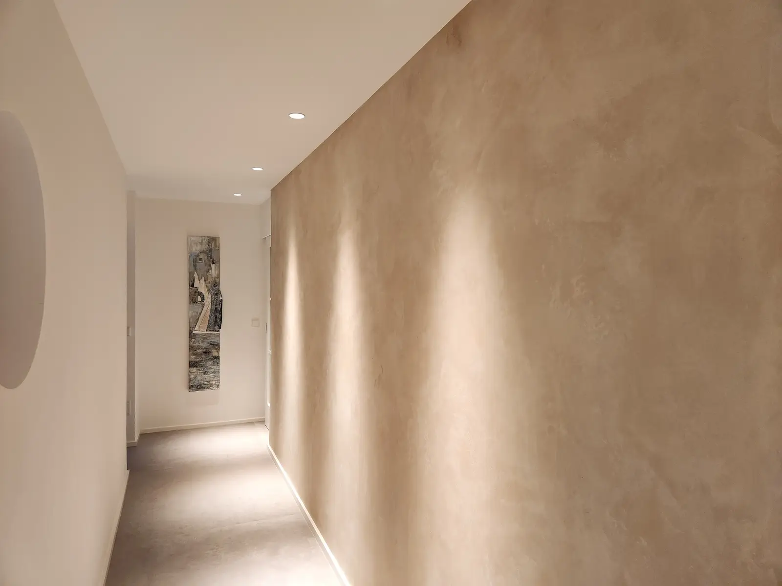 Geglätteter Kalkputz in warmem Beige an einer langen Flurwand, von unten beleuchtet