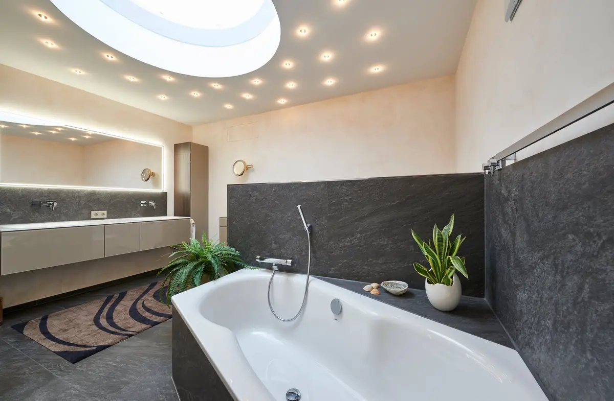 Badezimmer mit hellem Kalkputz und dunkler Wanne